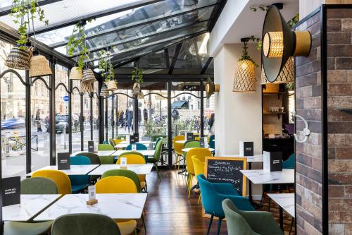 un restaurante con mesas y sillas amarillas y azules en Hotel Observatoire Luxembourg, en París