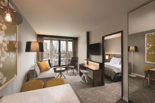 a hotel room with a bed and a mirror at Adina Apartment Hotel Frankfurt Westend in Frankfurt