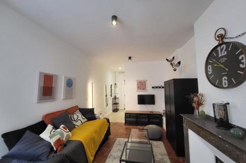 un salon avec un canapé et une horloge au mur dans l'établissement Nice and bright studio in the center of Toulouse, à Toulouse