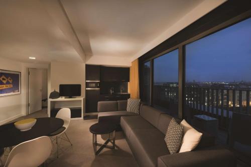a living room with a couch and a large window at Adina Apartment Hotel Berlin Hackescher Markt in Berlin