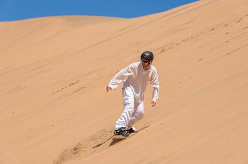 a man riding a snowboard down a sand dune at The Timeless Way Self Catering Accommodation in Swakopmund