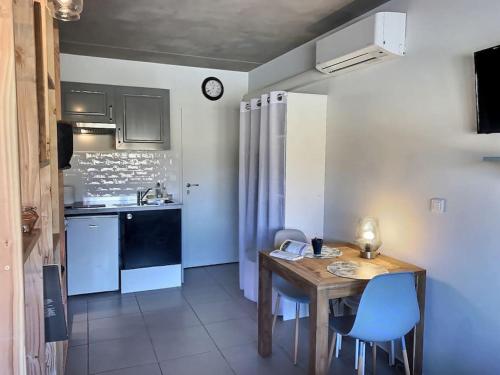 eine kleine Küche mit einem Holztisch und blauen Stühlen in der Unterkunft Le Saint Roch 2 - AC CLIM - WIFI - 50m Centre ville in Avignon