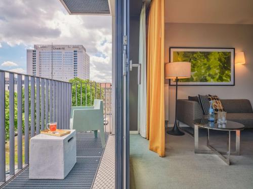 a room with a balcony with a view of a city at Adina Apartment Hotel Berlin Mitte in Berlin