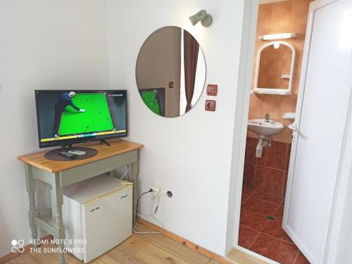 a television on a table in a bathroom with a mirror at Guest House Sunflowers in Pomorie