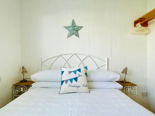 a bedroom with a white bed with a star on the wall at Lucy Lou, charming holiday bungalow in Devon in Galmpton-on-the-Dart