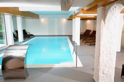 a swimming pool in the middle of a room with chairs at Naturhotel Café Waldesruhe in Oberstdorf