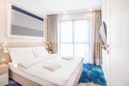 a bedroom with a white bed with a blue floor at VacationClub - Boulevard Residence Apartament 11 in Ustronie Morskie