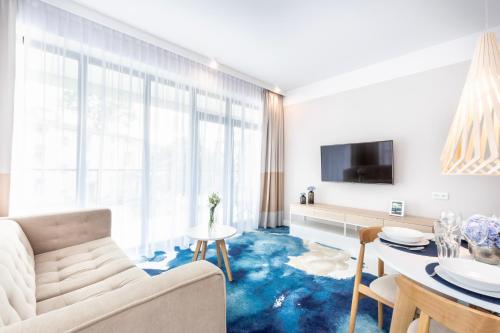 a living room with a blue carpet at VacationClub - Boulevard Residence Apartament 11 in Ustronie Morskie
