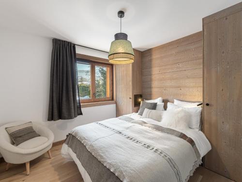 une chambre avec un lit, une chaise et une fenêtre dans l'établissement Appartement neuf avec sauna, hammam et salle de sport - FR-1-569-41, à Megève