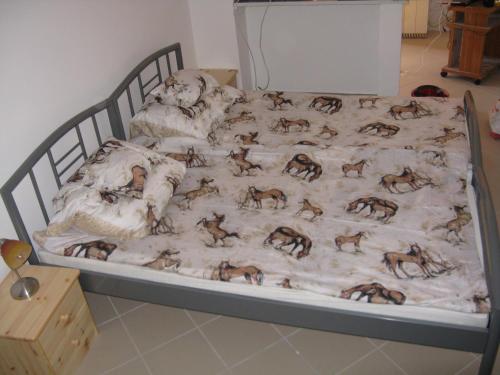 a bed with a blanket with horses on it at Kárpáti Motel in Budapest