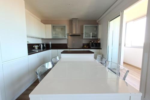 - une cuisine blanche avec une grande table et des chaises dans l'établissement Spacious and bright cocoon near the sea, à Bandol