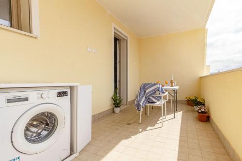 a laundry room with a washing machine and a table at Skyfive Water Apartment in Alghero