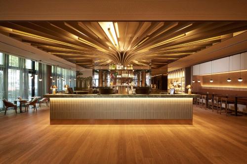 Adina Apartment Hotel Dusseldorf في دوسلدورف: مطعم به بار به طاولات وكراسي