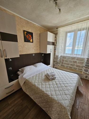 a bedroom with a bed with a white blanket and a window at Lanterna Apartments in Kotor