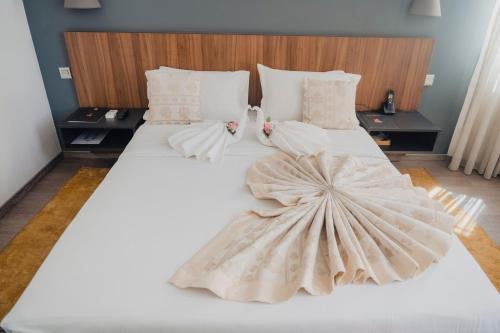 Dos camas con sábanas blancas y un vestido. en Hotel Nina, en Dakar