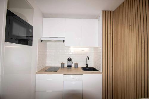 eine Küche mit weißen Schränken, einem Waschbecken und einem TV in der Unterkunft Nice quiet nest near Fréjus Plage and Port Fréjus in Fréjus