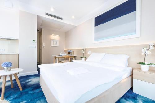 a bedroom with a large white bed and a table at VacationClub - Boulevard Residence Apartament 14 in Ustronie Morskie