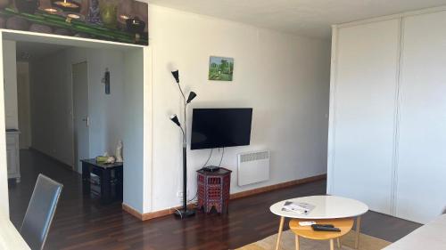 a living room with a television and a table at MER & SOLEIL in Morsiglia