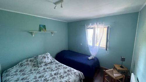 Dormitorio azul con cama y ventana en MER & SOLEIL en Morsiglia