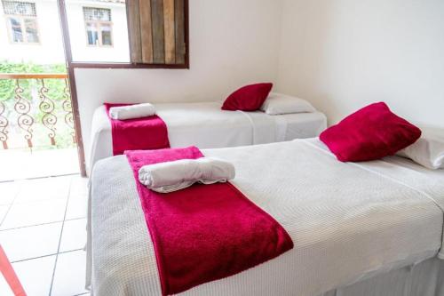 two beds in a room with red and white towels at Pousada Baobá in Olinda