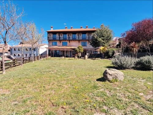 una casa grande en lo alto de un campo de hierba en Hotel Rural Candela y Plata, en Puerto de Béjar