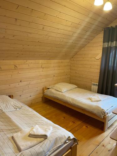 a room with two beds in a wooden cabin at Sosnowy Domek Piętro in Graboszyce