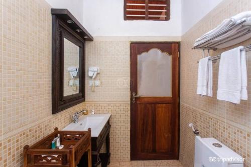 a bathroom with a sink and a toilet and a mirror at Mizingani Seafront Hotel in Zanzibar City