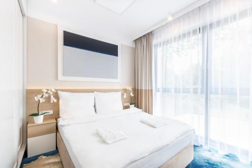 une chambre blanche avec un grand lit et une fenêtre dans l'établissement VacationClub - Boulevard Residence Apartament 22, à Ustronie Morskie