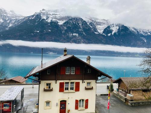 a house with red shutters and a lake and mountains at LakeSide Villa - 18 in Niederried