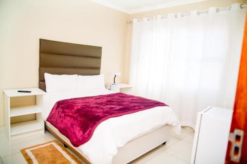 a bedroom with a large bed with a purple blanket at AS Guesthouse & Self-catering in Swakopmund