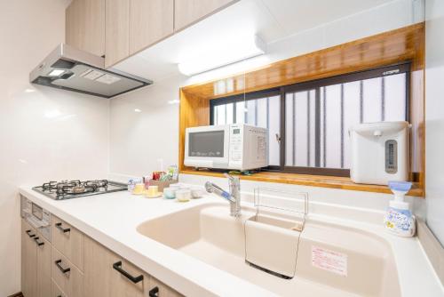 a kitchen with a sink and a microwave and a window at JR 66sqm 1F Family Suite 2LDK JR Koiwa-Keisei Koiwa-Asakusa-Oshiage-Shinjuku-Ueno in Tokyo