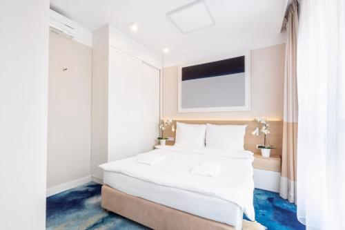 - une chambre avec un grand lit blanc et une fenêtre dans l'établissement VacationClub - Boulevard Residence Apartament 31, à Ustronie Morskie