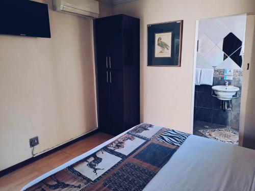 ein Schlafzimmer mit einem Bett, einem Schrank und einem Waschbecken in der Unterkunft Ecotel Premier Lodge & Conference Centre in Benoni