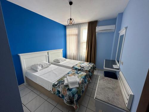 1 dormitorio con 2 camas y pared azul en Maren City Apart Hotel, en Alanya