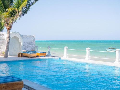 a swimming pool next to a beach with the ocean at Villa Paradis by Casa Paradis in Jambiani