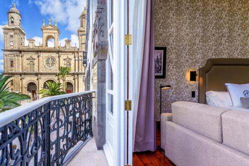 a room with a balcony with a view of a church at Boutique Hotel Cordial Plaza Mayor de Santa Ana in Las Palmas de Gran Canaria