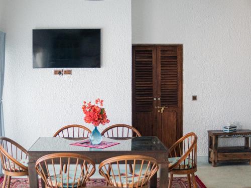 a dining room table with chairs and a vase of flowers at Villa Paradis by Casa Paradis in Jambiani