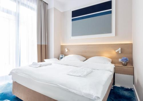 a bedroom with a large bed with white sheets at VacationClub - Boulevard Residence Apartament 33 in Ustronie Morskie