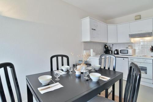 une cuisine avec une table et des chaises noires et une cuisine avec des appareils blancs dans l'établissement Le Jean Bart - À 20m de la plage, à Saint-Cast-le-Guildo