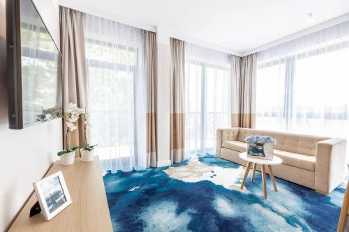 a living room with a couch and a blue carpet at VacationClub - Boulevard Residence Apartament 33 in Ustronie Morskie