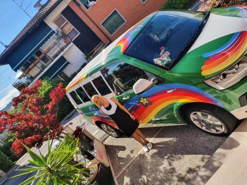 a woman standing in front of a bus with a rainbow at Hotel Virginia in Garda