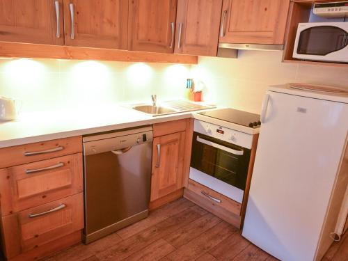 une cuisine avec des armoires en bois et un réfrigérateur blanc dans l'établissement Charmant Triplex 6 pers, 50m télécabine Sétaz, cœur de Valloire, balcon sud - FR-1-263-286, à Valloire