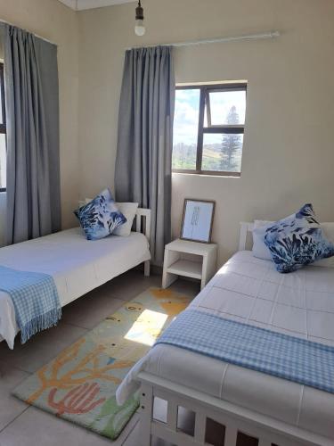 a bedroom with two beds and a chair at No 12 Tugela Mouth in Tugela Mouth