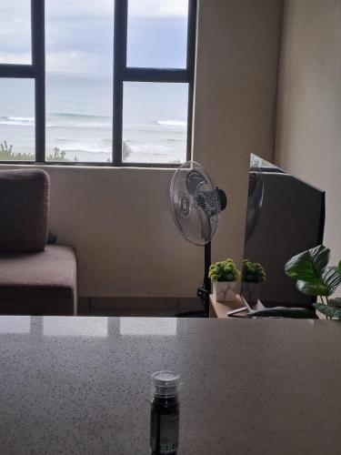 a living room with a desk with a fan and a window at No 12 Tugela Mouth in Tugela Mouth