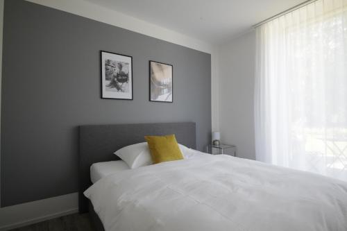 a bedroom with a white bed with a yellow pillow at VARIAS Lifestyle Apartments in Elsau