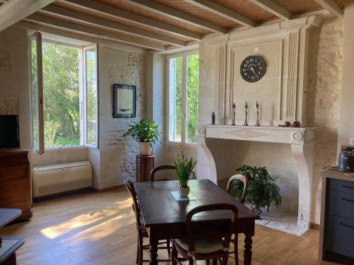 une salle à manger avec une table et une cheminée dans l'établissement Les Ganivelles, à Saint-Dizant-du-Gua