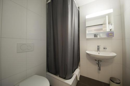 a bathroom with a toilet a sink and a shower at VARIAS Lifestyle Apartments in Elsau