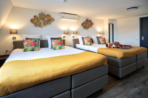 two beds in a room with yellow cushions at Bed and Breakfast De Heren van Valkenburg in Valkenburg