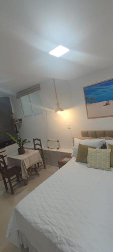 a bedroom with a large white bed and a table at Residencial Temporada Aracaju in Aracaju