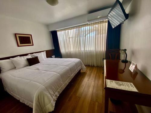 1 dormitorio con cama, escritorio y ventana en Faraona Grand Hotel, en Lima